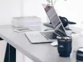 Biurko z laptopem, telefonem i słuchawkami. Chcesz wiedzieć, jak zahasłować folder?