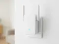 Biały wzmacniacz Wi-Fi z antenkami, podłączony do gniazdka. Pokazuje, jak działa wzmacniacz Wi-Fi, rozszerzając zasięg sieci.