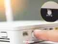 Palec naciska przycisk WPS na routerze, ułatwiając połączenie z siecią Wi-Fi.