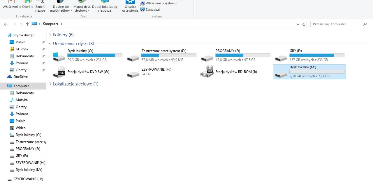 Widok folderów systemu Windows, gdzie widać dyski, w tym "SZYFROWANIE (H:)", co może być pomocne, gdy zastanawiasz się, jak zaszyfrować folder.