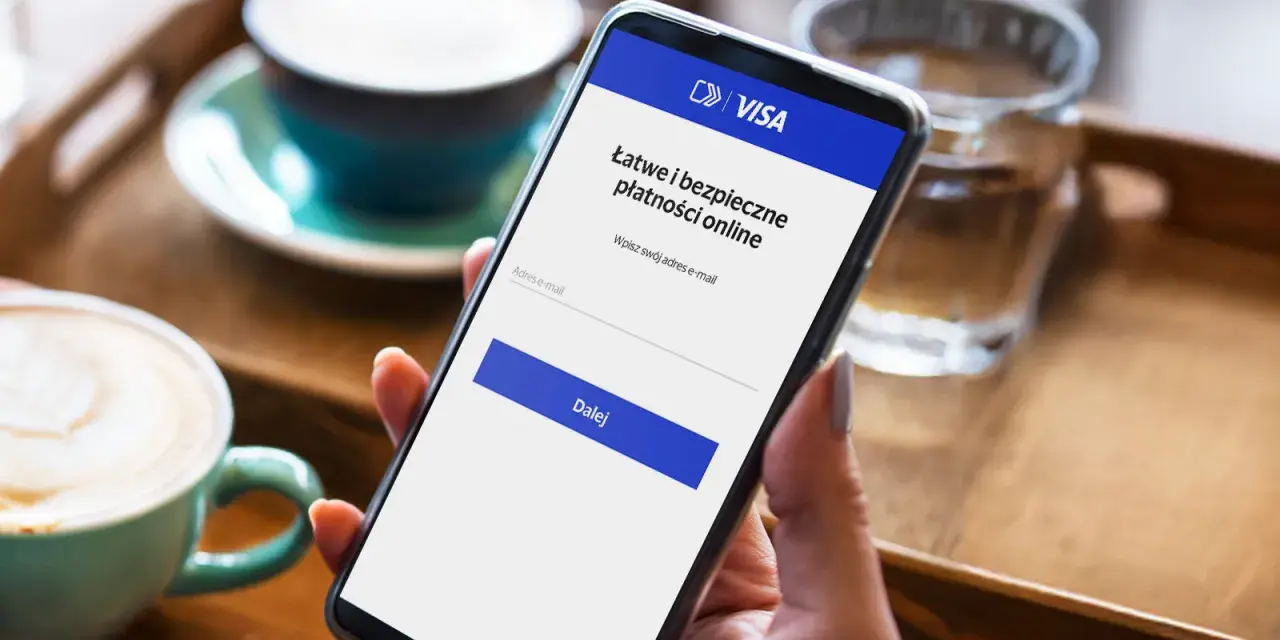 Kobieta używa telefonu do łatwej i bezpiecznej płatności kartą w internecie. Na ekranie widnieje logo VISA i pole do wpisania adresu e-mail.