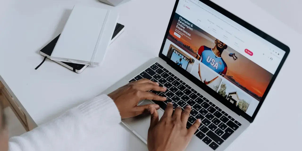 Osoba pisze na klawiaturze laptopa, na ekranie którego widać stronę z ofertami podróży. Przeglądarki internetowe otwierają świat możliwości.