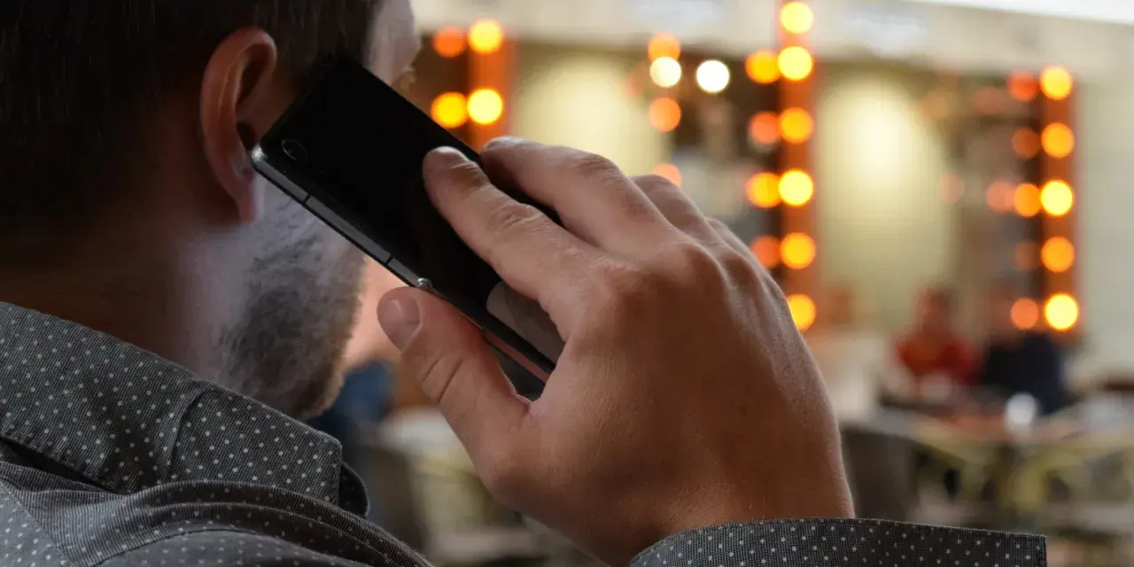 Mężczyzna rozmawia przez telefon, zastanawiając się, co to jest catfishing i czy sam nie jest jego ofiarą.