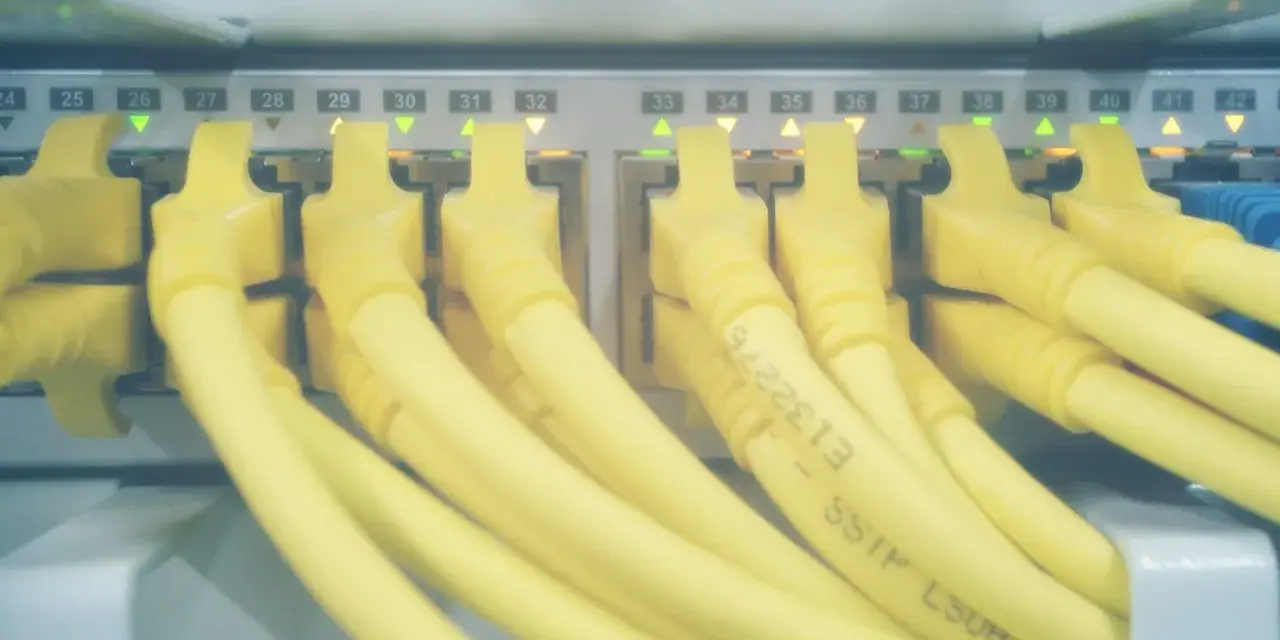 Żółte kable sieciowe podłączone do portów serwera. Zielone i pomarańczowe diody sygnalizują aktywność, a numery portów od 24 do 42 wskazują, które hosts windows są podłączone.