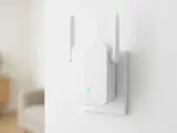 Biały wzmacniacz Wi-Fi z antenkami, podłączony do gniazdka. Pokazuje, jak działa wzmacniacz Wi-Fi, rozszerzając zasięg sieci.