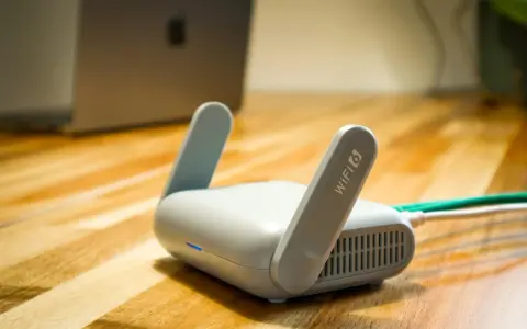 Router Wi-Fi 6 z antenkami, obok laptopa. Czy wiesz, upnp co to? Ułatwia komunikację urządzeń w sieci.