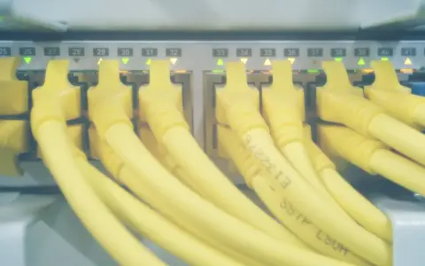 Żółte kable sieciowe podłączone do portów serwera. Zielone i pomarańczowe diody sygnalizują aktywność, a numery portów od 24 do 42 wskazują, które hosts windows są podłączone.