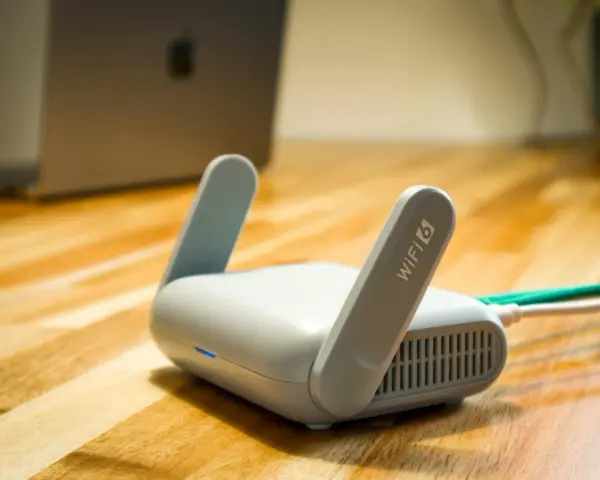 Router Wi-Fi 6 z antenkami, obok laptopa. Czy wiesz, upnp co to? Ułatwia komunikację urządzeń w sieci.