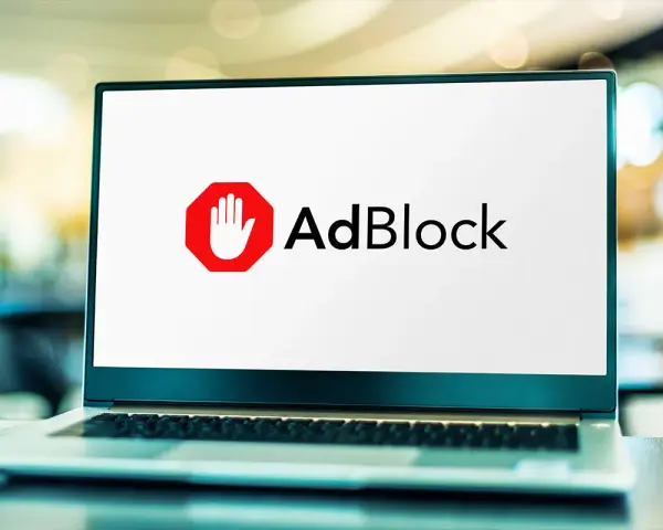 Laptop z logo AdBlock. Chcesz wiedzieć, jak wyłączyć adblocka na laptopie?