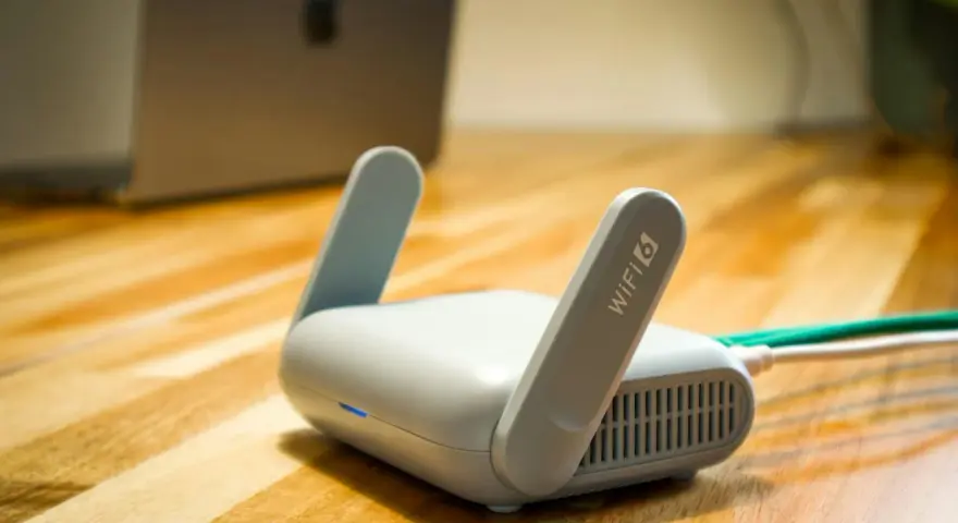 Router Wi-Fi 6 z antenkami, obok laptopa. Czy wiesz, upnp co to? Ułatwia komunikację urządzeń w sieci.