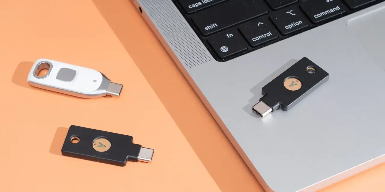 Trzy klucze bezpieczeństwa USB-C, które służą jako kod 2FA, leżą obok laptopa.
