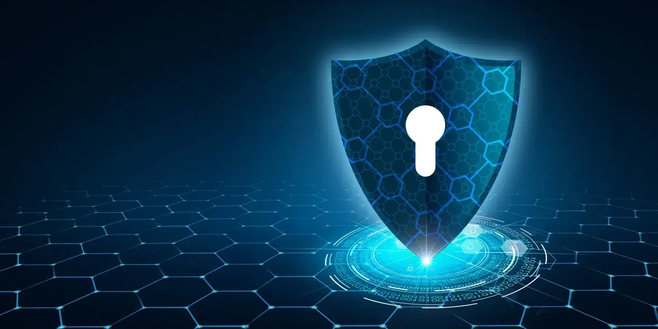 Tarcza z kluczem symbolizuje ochronę przed zagrożeniami, jak co to jest cyberatak. Sieć heksagonalna i kod binarny podkreślają cyfrowy świat.