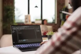 Programista pracuje nad kodem, edycja pliku hosts w tle.